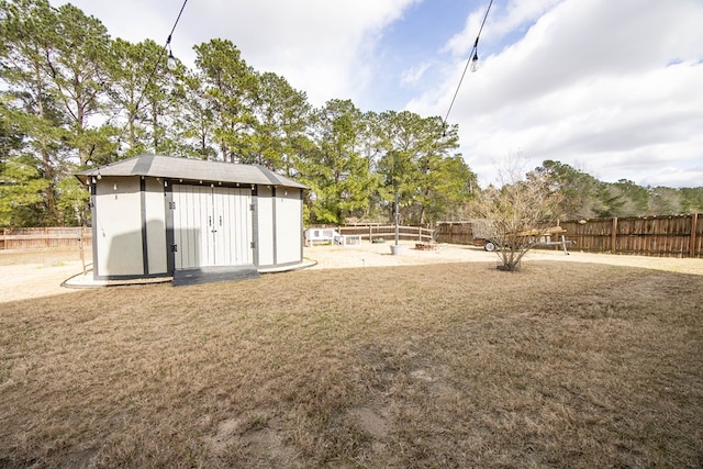 view of yard with an outbuilding, a fenced backyard, and a shed