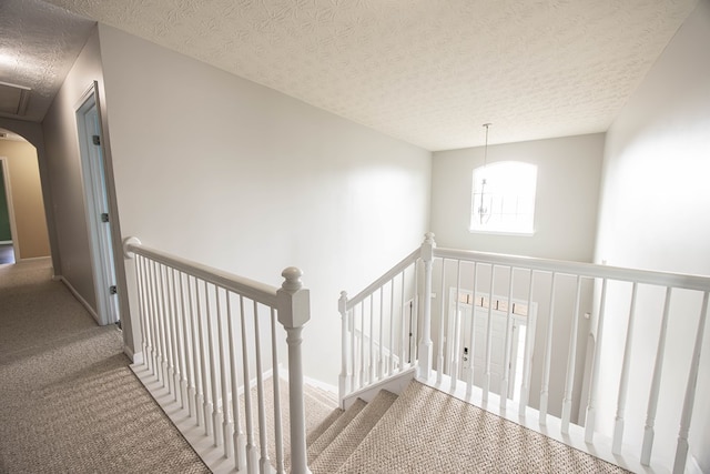 corridor with arched walkways, carpet flooring, and a textured ceiling