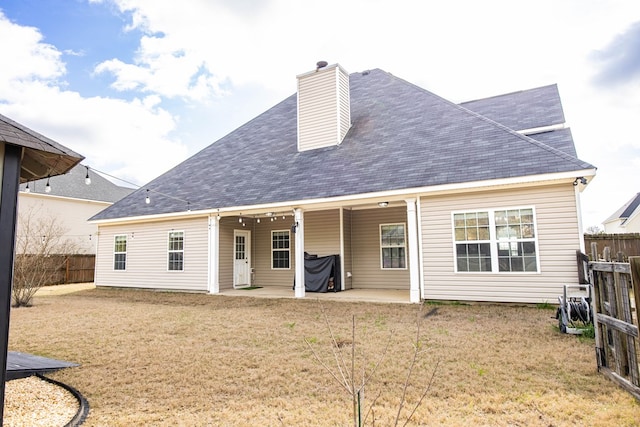 back of property with a lawn, a chimney, a patio, and fence