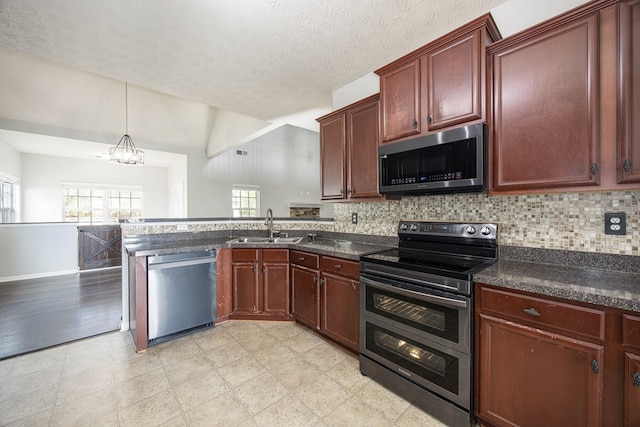 kitchen featuring a sink, tasteful backsplash, reddish brown cabinets, appliances with stainless steel finishes, and a peninsula