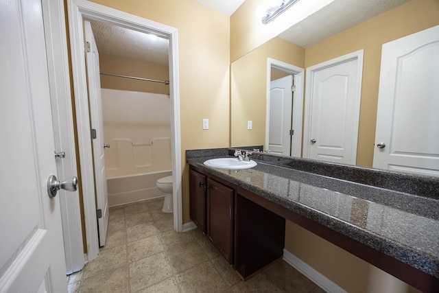 bathroom featuring baseboards, toilet, vanity, bathing tub / shower combination, and a textured ceiling