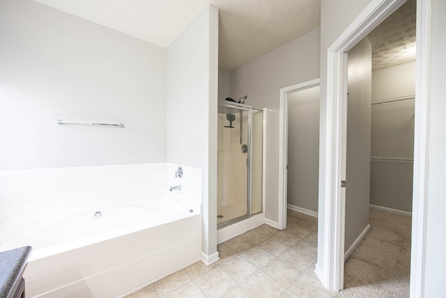 full bathroom with baseboards, a shower stall, a spacious closet, a textured ceiling, and a garden tub