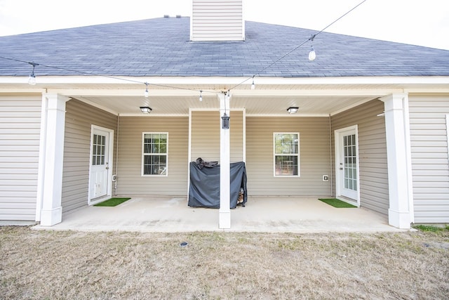 exterior space featuring a chimney, a shingled roof, and a patio