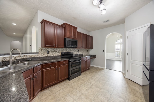 kitchen featuring visible vents, decorative backsplash, arched walkways, stainless steel appliances, and a sink