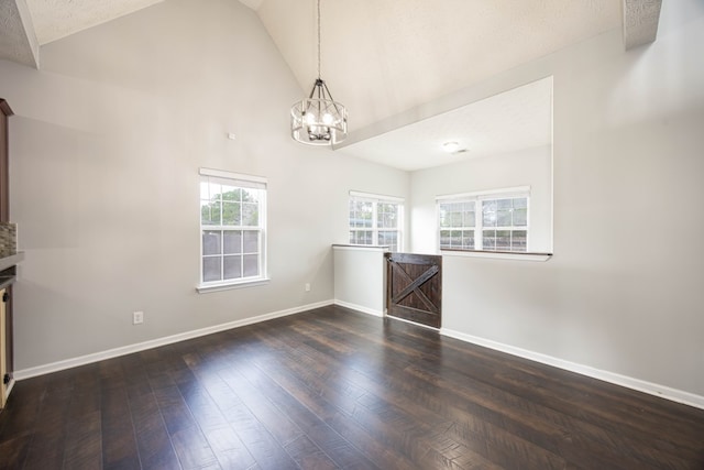 unfurnished dining area featuring dark wood-style floors, a chandelier, high vaulted ceiling, and baseboards