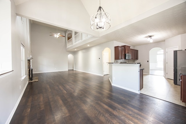 kitchen with arched walkways, appliances with stainless steel finishes, open floor plan, and dark wood-style flooring