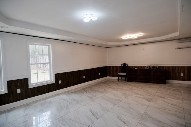 spare room featuring a raised ceiling, a wall mounted air conditioner, and wooden walls