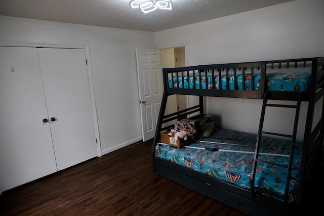 bedroom with a closet, dark hardwood / wood-style floors, and a textured ceiling