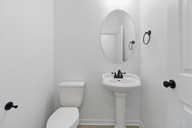 bathroom with toilet, baseboards, and tile patterned flooring
