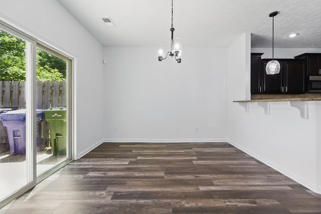 unfurnished dining area featuring dark wood-type flooring, a chandelier, baseboards, and recessed lighting