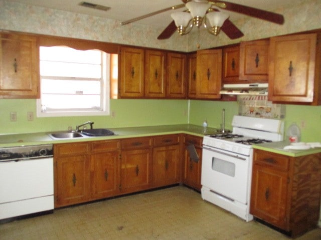 kitchen with under cabinet range hood, white appliances, a sink, visible vents, and brown cabinetry