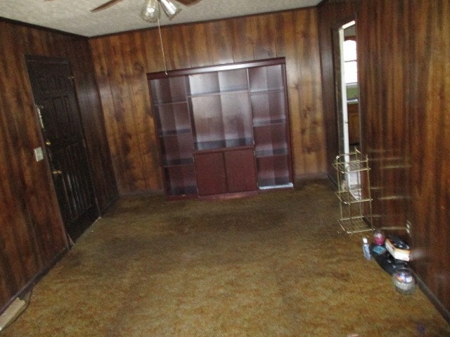 spare room featuring a ceiling fan and wooden walls