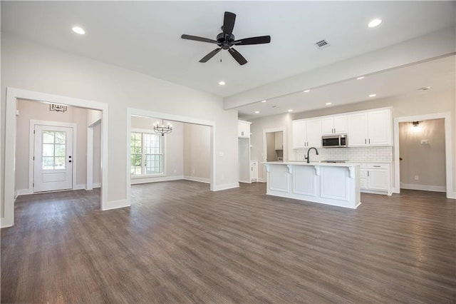 unfurnished living room with sink, dark wood-type flooring, and ceiling fan with notable chandelier