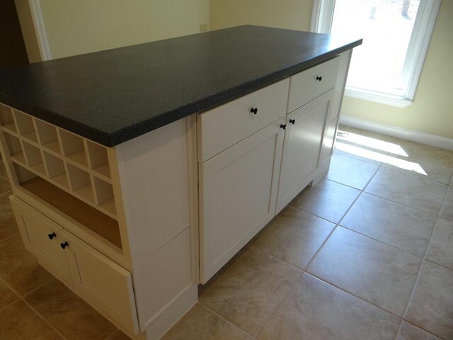 kitchen with white cabinets, light tile patterned floors, and a kitchen island