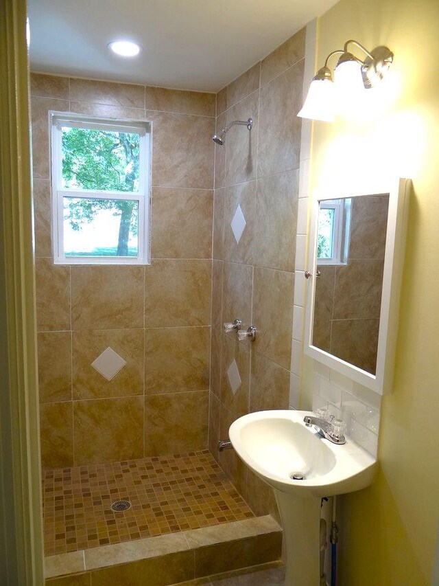 bathroom with a tile shower, decorative backsplash, and sink