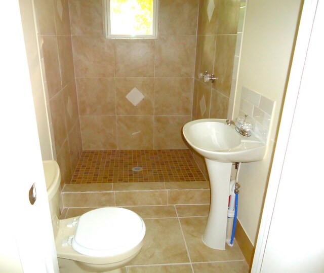 bathroom featuring a tile shower, toilet, and tile patterned floors