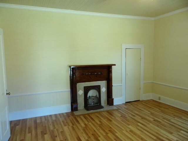 unfurnished living room featuring light wood-type flooring and ornamental molding