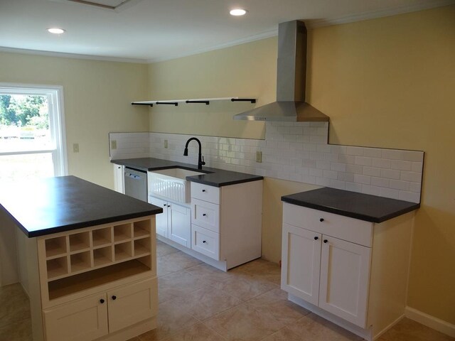 kitchen featuring dishwasher, wall chimney range hood, sink, tasteful backsplash, and white cabinetry