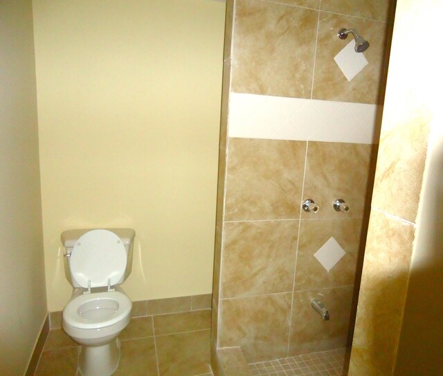 bathroom featuring tile patterned floors, toilet, and tiled shower