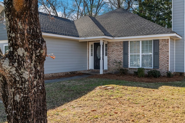 ranch-style house featuring roof with shingles, brick siding, and a front lawn