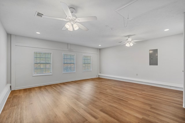 empty room featuring visible vents, attic access, a textured ceiling, wood finished floors, and electric panel