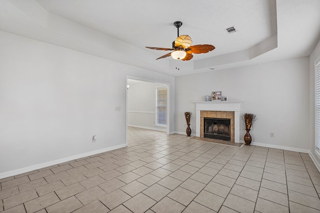 unfurnished living room featuring a raised ceiling, visible vents, a fireplace, and baseboards