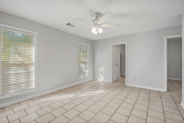 unfurnished room featuring light tile patterned floors, visible vents, ceiling fan, a textured ceiling, and baseboards