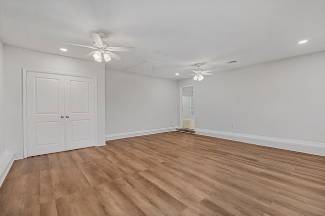 empty room with attic access, recessed lighting, light wood-style flooring, and baseboards