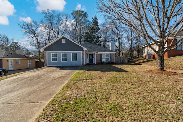 view of front facade featuring brick siding, a chimney, a front yard, fence, and driveway