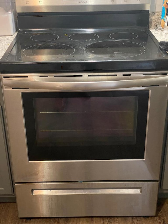 interior details featuring stainless steel electric range oven and dark wood-type flooring