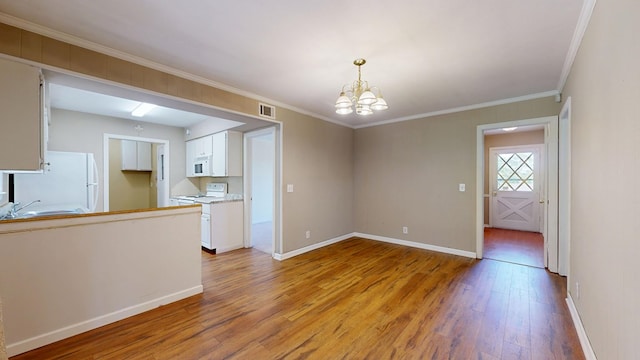 spare room with light wood-style flooring, a chandelier, baseboards, crown molding, and a sink