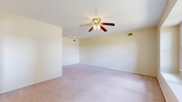 empty room with a ceiling fan, light carpet, and baseboards