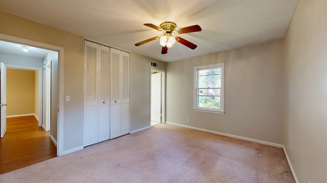 unfurnished bedroom with carpet flooring, a closet, baseboards, and ceiling fan