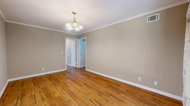 spare room with wood finished floors, a chandelier, baseboards, and ornamental molding