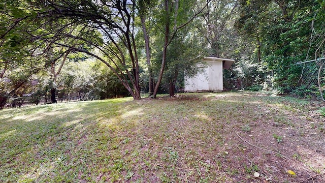 view of yard featuring a storage shed, an outbuilding, and a view of trees