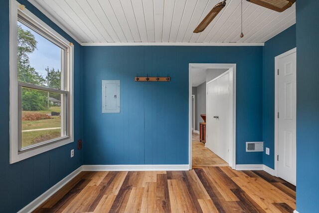 unfurnished room with ornamental molding, wood ceiling, wooden walls, hardwood / wood-style floors, and electric panel