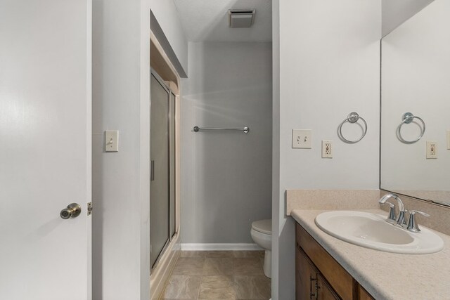 bathroom with a textured ceiling, vanity, toilet, and an enclosed shower