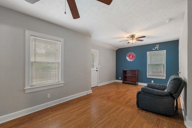 sitting room with wood-type flooring, a textured ceiling, and ceiling fan