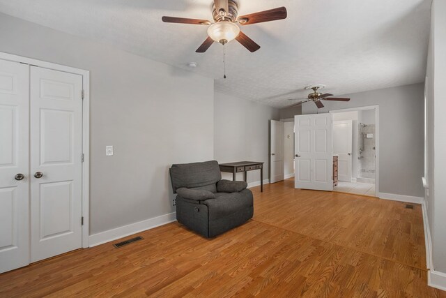 sitting room featuring wood-type flooring, a textured ceiling, and ceiling fan