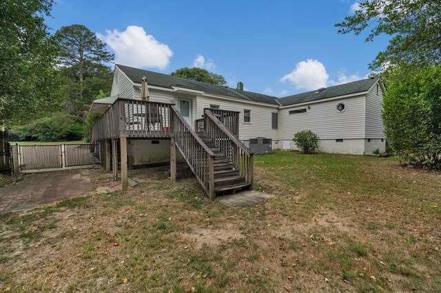 back of property with a wooden deck, a yard, and cooling unit