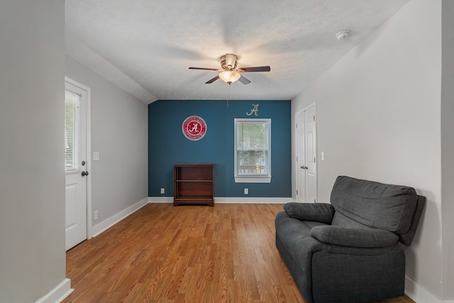 living area featuring ceiling fan, a healthy amount of sunlight, a textured ceiling, and light hardwood / wood-style flooring