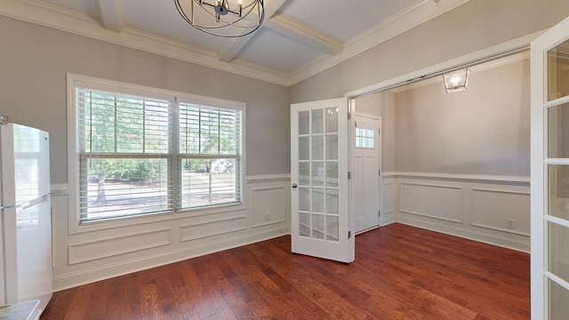 empty room with a notable chandelier, wainscoting, a decorative wall, and coffered ceiling