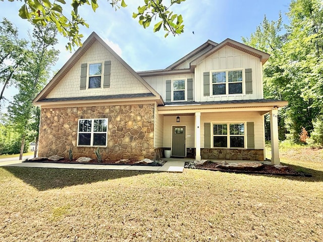 craftsman house with covered porch, a front yard, stone siding, and board and batten siding