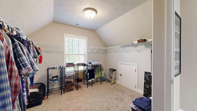 walk in closet featuring vaulted ceiling, carpet flooring, and visible vents