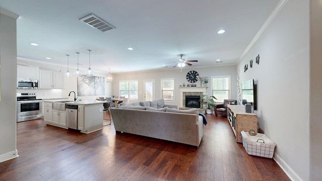 living room featuring ornamental molding, visible vents, recessed lighting, a ceiling fan, and a tiled fireplace