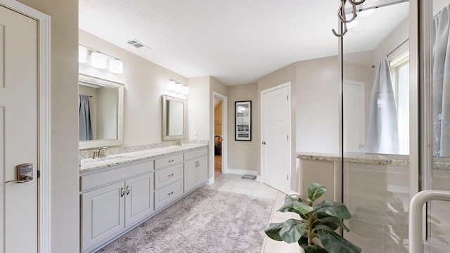 full bathroom with double vanity, tile patterned floors, visible vents, and a sink