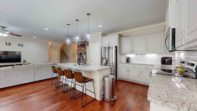 kitchen featuring ornamental molding, stainless steel appliances, a kitchen breakfast bar, and open floor plan