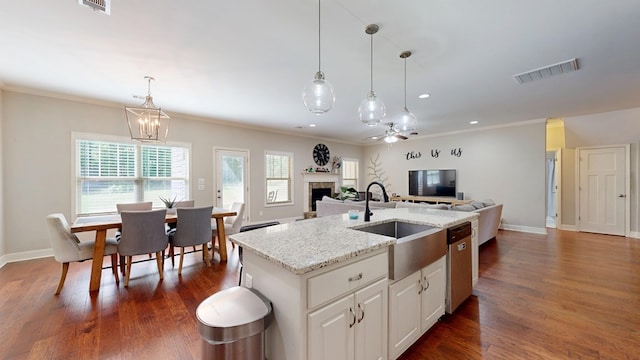 kitchen featuring stainless steel dishwasher, visible vents, a sink, open floor plan, and a fireplace