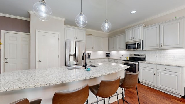 kitchen with a sink, dark wood finished floors, backsplash, appliances with stainless steel finishes, and ornamental molding