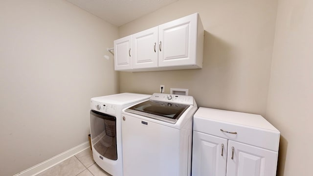 laundry area with baseboards, light tile patterned flooring, cabinet space, and washer and clothes dryer